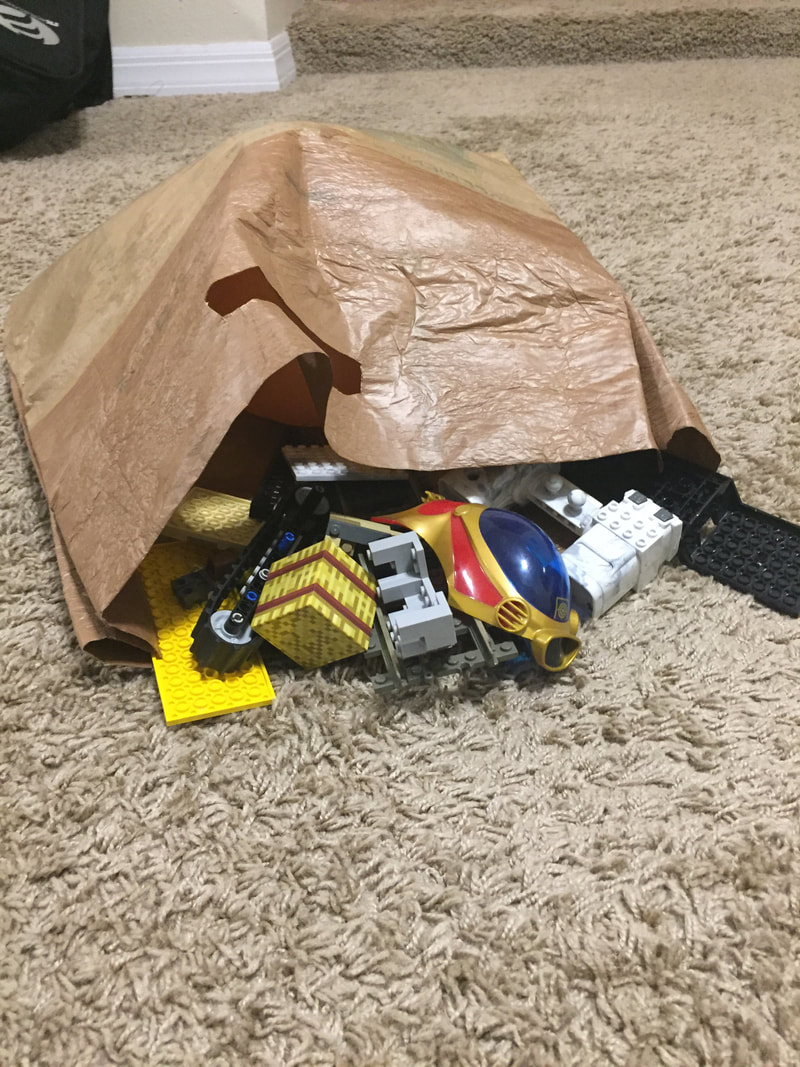 Plabric bag laying on the ground with toys spilling out